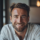 Homme souriant dans un café chaleureux.